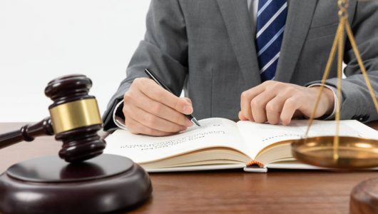 closeup-shot-person-writing-book-with-gavel-table (1)