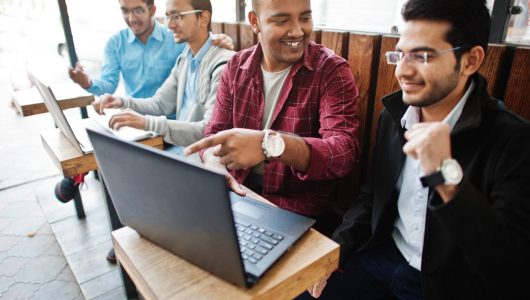 group-four-indian-teen-male-students-classmates-spend-time-together-work-laptops